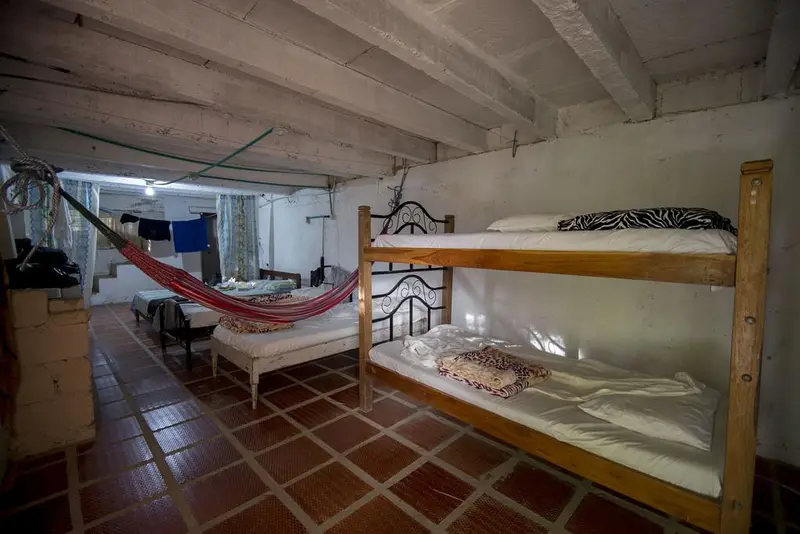 A wooden bunk bed beside a hammock in a room with terracotta floor tiles