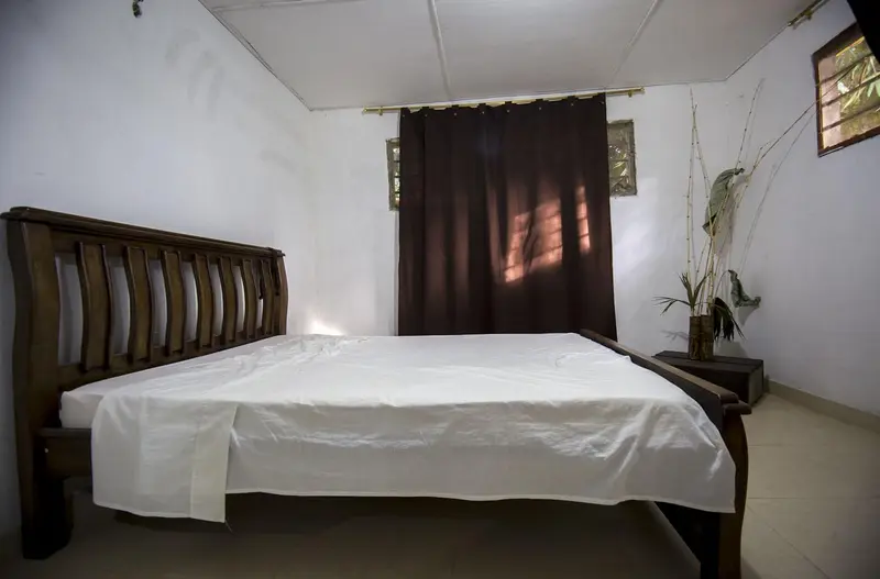 A bedroom with a large bed and dark headboard, a brown curtain in the doorway