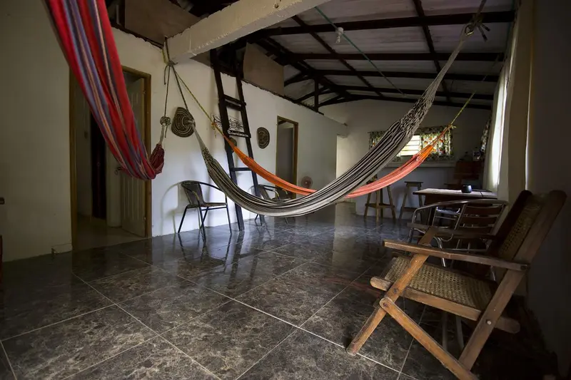 Two hammocks strung across the open common room with chairs and a dining table