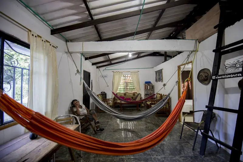 Wide view of the common room: an orange hammock in front, a ladder, white walls and a metal roof