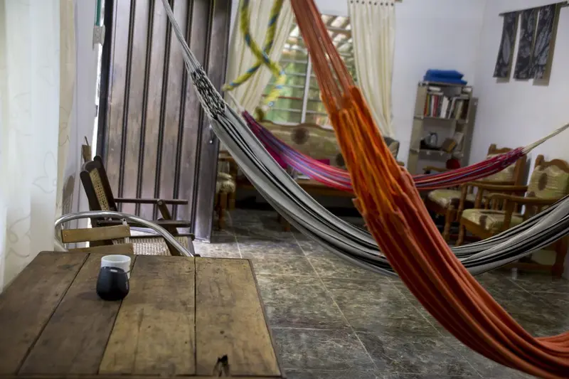 A striped hammock and a red hammock hanging over a wooden table in the common room
