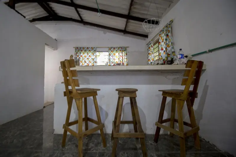 A white breakfast bar with three tall wooden stools in front of the kitchen