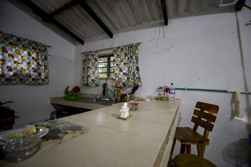 A long kitchen counter under windows with colourful patchwork curtains, a wooden chair at the end