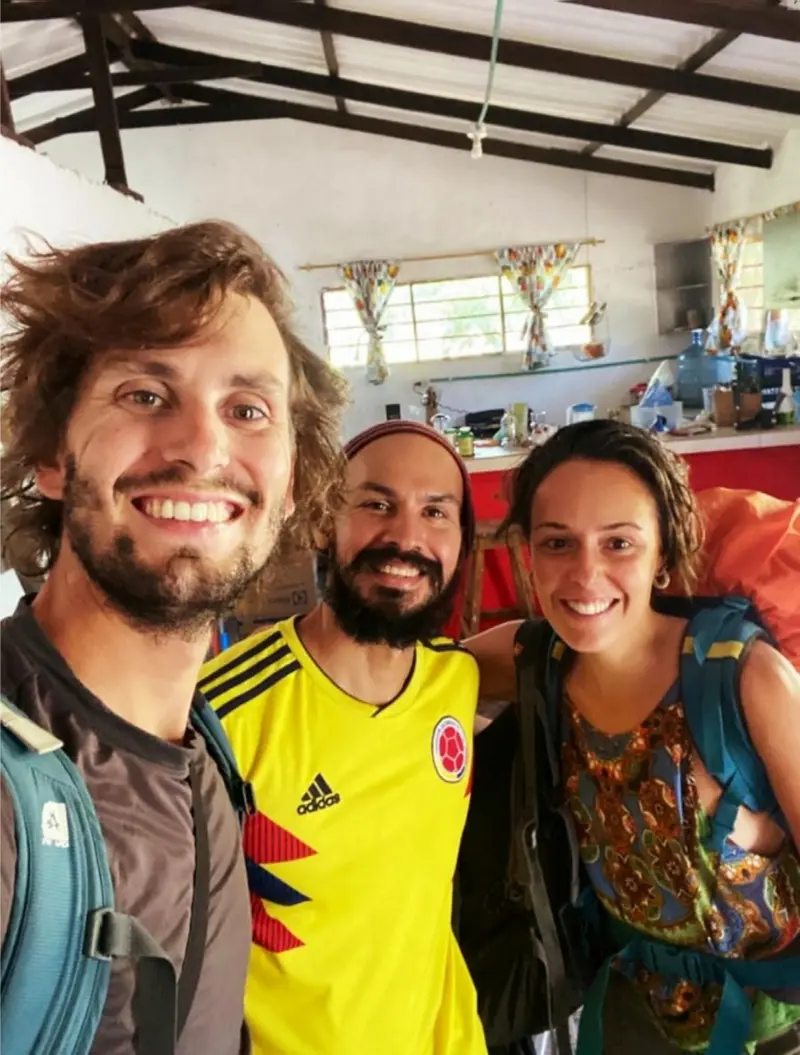 Three smiling travellers taking a selfie in the house, one in a yellow Colombia football shirt