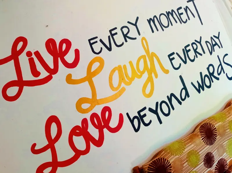 Hand-painted wall lettering in red, yellow and navy: Live every moment, Laugh every day, Love beyond words